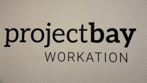 Ein Wandtattoo mit der Aufschrift „projectbay Workation“, dem Hostel für Schreibtischtäter