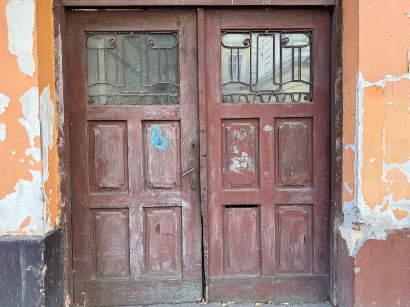 sehr stark beschädigtes zweiflügeliges Tor in kaputter Hauswand