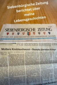 Zeitungsausschnitt der Siebenbürgischen Zeitung mit dem Artikel ‚Motters Knoblauchwurst – Rezepte überleben Kriege‘, darüber ein Schriftzug: ‚Siebenbürgische Zeitung berichtet über meine Lebensgeschichten.