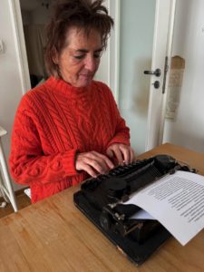 Autorin Irmgard Rosina tippt konzentriert an einer alten Schreibmaschine – analoges Schreiben als bewusster Gegenpol zur KI.