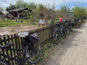 Fahrräder stehen an einem Holzzaun in einem Garten im Frühling, grüne Wiese und ländliche Atmosphäre passend zum Gedicht „Frühling und sein blaues Band“.
