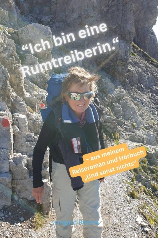 Frau mit Rucksack wandert lächelnd durch eine felsige Berglandschaft. Über dem Bild steht der Text „Ich bin eine Rumtreiberin“.