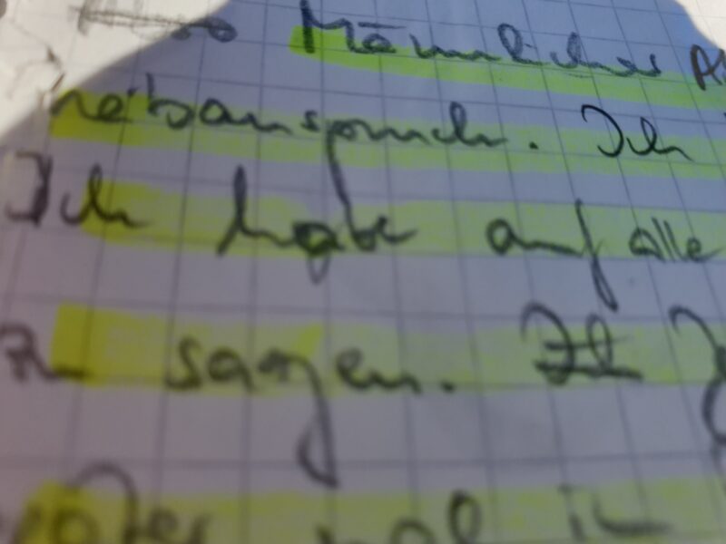 Handgeschriebene Notizen mit gelb markierten Zeilen in einem karierten Notizbuch