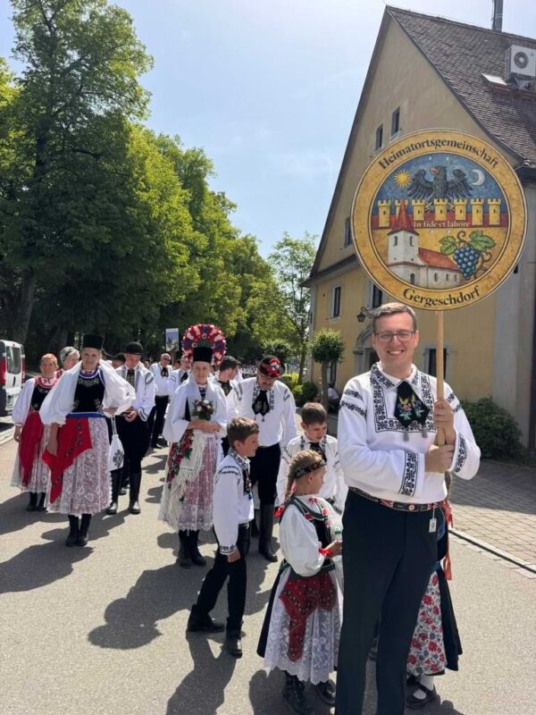Trachtengruppe der HOG Gergeschdorf beim Trachtenumzug des Heimattags der Siebenbürger Sachsen in Dinkelsbühl mit Kindern, Erwachsenen und Heimatschild in traditioneller siebenbürgisch-sächsischer Tracht.
