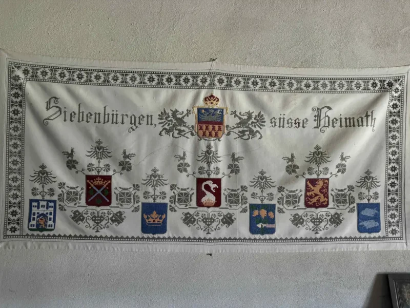 Gesticktes Wandtuch mit der Aufschrift „Siebenbürgen, süße Heimat“ und siebenbürgischen Wappen – Symbol für Herkunft, Heimat und Familiengeschichte.